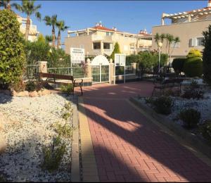 a brick walkway with benches in a park at 2 bedroom Duplex Apartment Playa Flamenca in Orihuela Costa