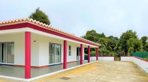 a building with red pillars in a yard at Chalé d'Angra Guest House in Angra do Heroísmo