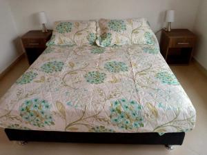 a bed with a flowered comforter with two night stands at Cabañas San Miguel Arcángel in San Gil +32 photos