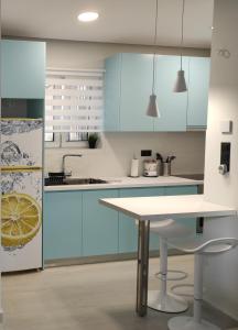 a kitchen with blue cabinets and a white table at Polyxenia’s Πλησίον Υγεία - Μητέρα - Ιασώ - ΟΑΚΑ in Athens