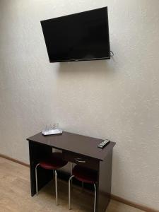 einen Schreibtisch mit 2 Stühlen und einen TV an der Wand in der Unterkunft Hotel and Entertaiment Complex Vlada in Tscherkassy