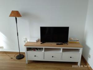 einen Fernseher auf einer weißen Kommode mit Lampe in der Unterkunft Sunny Home in Ferrol