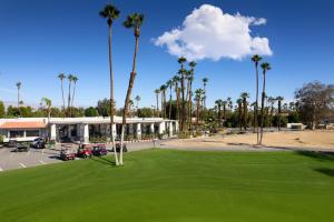 a golf course with palm trees and a building at Desert Oasis by Vacation Club Rentals in Cathedral City