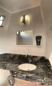 a bathroom with a sink and a mirror at Poupahotel Unidade Bairro in Taubaté