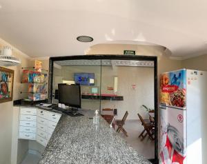 a kitchen with a refrigerator and a television in it at Poupahotel Unidade Bairro in Taubaté