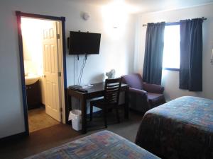 a hotel room with a desk and a chair at Nisutlin Trading Post Motel in Teslin