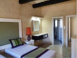 a bedroom with a bed and a bathroom with a sink at Petra Farmhouse B&B in Nadur