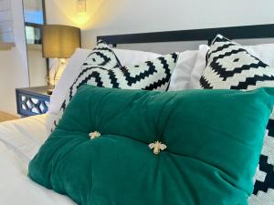 a green pillow on a bed with black and white pillows at Stylish studio apartment in centre of St Clears in St Clears