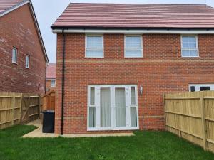 a brick house with a white door and a fence at The Joyland House in Romsey