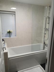 a bathroom with a bath tub with a vase of flowers at The Joyland House in Romsey +17 photos