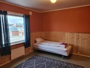 Cette petite chambre comprend un lit et une fenêtre. dans l'établissement Festningsgaten 3 b, à Vardø