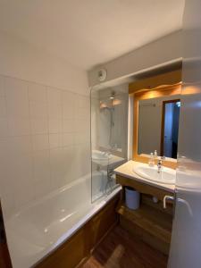 a bathroom with a tub and a sink and a mirror at Residence la Dame Blanche 1800 in Puy-Saint-Vincent