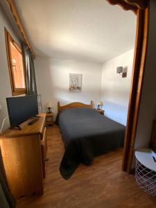 a bedroom with a bed and a desk with a television at Residence la Dame Blanche 1800 in Puy-Saint-Vincent
