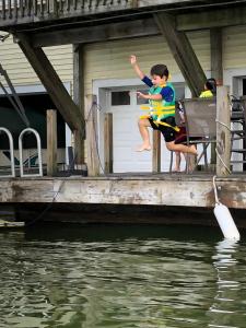 Un jeune garçon saute d'un quai dans l'eau dans l'établissement Lake Front Home Near Peek'n Peak, à Findley Lake