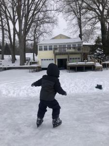 a young child playing in the snow in front of a house at Lake Front Home Near Peek'n Peak in Findley Lake