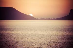 a sunset over the water with mountains in the background at Gran H La Marina in Altea