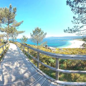 a bench on a boardwalk overlooking a beach at Hostal Cachiño in San Mamede de Carnota