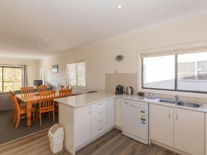 a kitchen with white cabinets and a dining room with a table at Alaska 2 8 Poley Cow Lane in Jindabyne