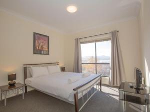 a bedroom with a bed and a large window at Alaska 2 8 Poley Cow Lane in Jindabyne