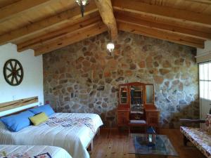 1 dormitorio con 2 camas y pared de piedra en Cabañas Walddorf - Alcatraz, en Atemajac de Brizuela