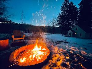 Livingston ManorCozy Cottage with Jacuzzi and Fire Pit and Reading Nook!的雪中的一个火坑,有长凳