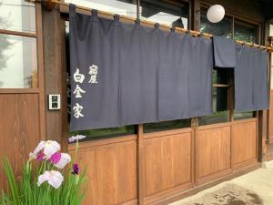 a building with a blue curtain and some flowers at 宿屋白金家 yadoya-shiroganeya 1日1組限定2名から8名様まで 全館貸切り 伝統的建造物の旅籠宿 Traditional culture experience in Nagano