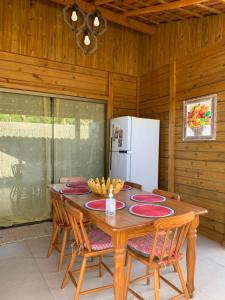 a dining room table with chairs and a white refrigerator at Pousada Portal da Praia in Anchieta