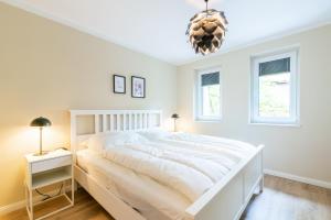 ein weißes Schlafzimmer mit einem Bett und zwei Fenstern in der Unterkunft Strandvilla Meeresblick Wohnung 03 in Boltenhagen