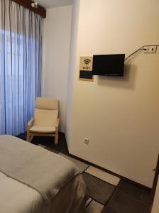 um quarto com uma cama e uma cadeira e uma televisão em Aveiro Theater Rooms em Aveiro