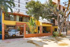 um edifício amarelo com uma cerca e uma árvore em Ayenda Casa Amarilla em Santa Marta