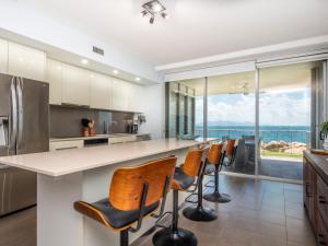 a kitchen with a bar with chairs and a view of the ocean at 1 Bright Point Apartment 4105 in Nelly Bay