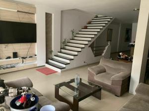 a living room with a staircase with a couch and a table at CASA ARENA - Hospedaje in Tumbes