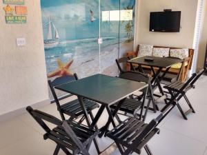uma sala de jantar com duas mesas e cadeiras e uma televisão em Suíte Sanlubia Enseada Guarujá no Guarujá