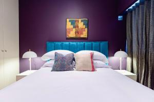 1 dormitorio con 1 cama blanca grande y paredes moradas en ✶ Maras Residence ✶ LUXURY Rooftop Pool & Grill, en Lima