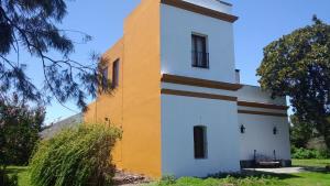 a white and yellow building with a tree at Estancia Rincón del San Francisco in Paysandú