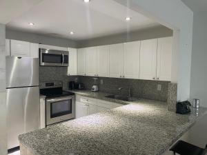 a kitchen with white cabinets and a granite counter top at Large 1 Bedroom apartment at Roney Palace Sleep 8 in Miami Beach