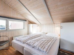 a bedroom with a large bed in a room with wooden walls at 6 person holiday home in Hvide Sande in Havrvig
