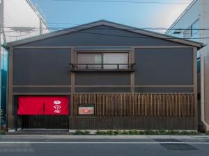 een zwart gebouw met een rode vlag ervoor bij YADOYA 烏丸院 in Tokyo