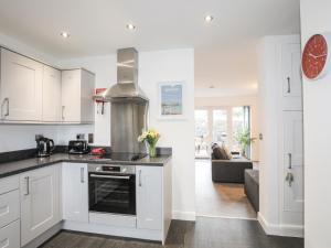 a kitchen with white cabinets and a stove top oven at Awel Deg Parc Delfryn in Brynteg