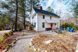 Ein weißes Haus mit einer Terrasse und blauen Stühlen in der Unterkunft Not Your Granny's Cottage in Black Mountain