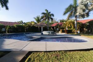 a pool with a bench in a yard with palm trees at Villaggio Claudia 29B in Potrero