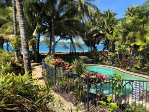 uma piscina com palmeiras e o oceano em Beach-Villa 4 em South Mission Beach
