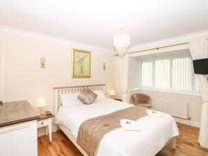 a white bedroom with a bed and a desk at Fairways in Woolacombe