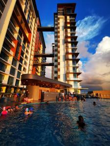 a group of people in a swimming pool next to buildings at Super Cozy and Stylish Micasa 3 home- Hann's Residence in Sibu
