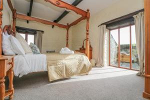 1 dormitorio con cama con dosel y ventana en Marhayes, en Camelford