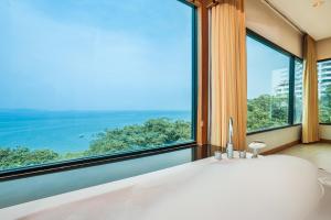 a window with a view of the ocean and mountains at Cosy Beach Hotel - SHA Extra Plus in Pattaya South