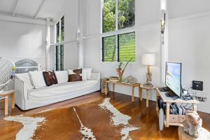 a white living room with a couch and a tv at Doorila Beach House in Bedarra Island