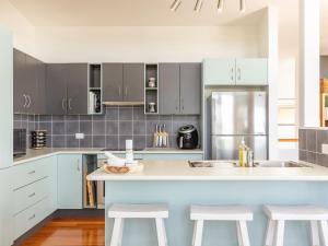 a kitchen with blue cabinets and a kitchen island with stools at Aiyana in Blueys Beach
