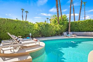 una piscina con 2 sillas y un barco. en California Dreamin' en Palm Springs