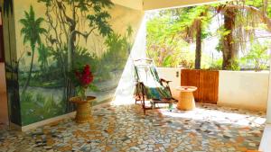 ein Zimmer mit einem Gemälde an der Wand und einem Stuhl in der Unterkunft Kasa KAÏSSAKU Idéale pour Surfeurs et Kitesurfeurs in Kafountine